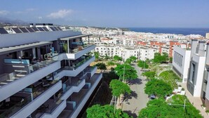 A modern building with multiple balconies overlooking a coastal cityscape. - Lme2ba- Cozy Ground Floor Flat in Luxury Resort (Estepona)