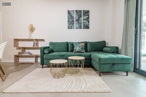 A modern living room with a green sofa, two round tables, a white rug, and a bookshelf. - Lme2ba- Cozy Ground Floor Flat in Luxury Resort (Estepona)