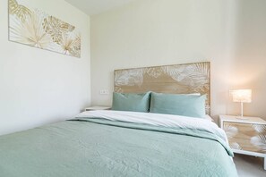 A bedroom with a bed, a nightstand, a wall-mounted lamp, and a wall art piece. - Lme2ba- Cozy Ground Floor Flat in Luxury Resort (Estepona)