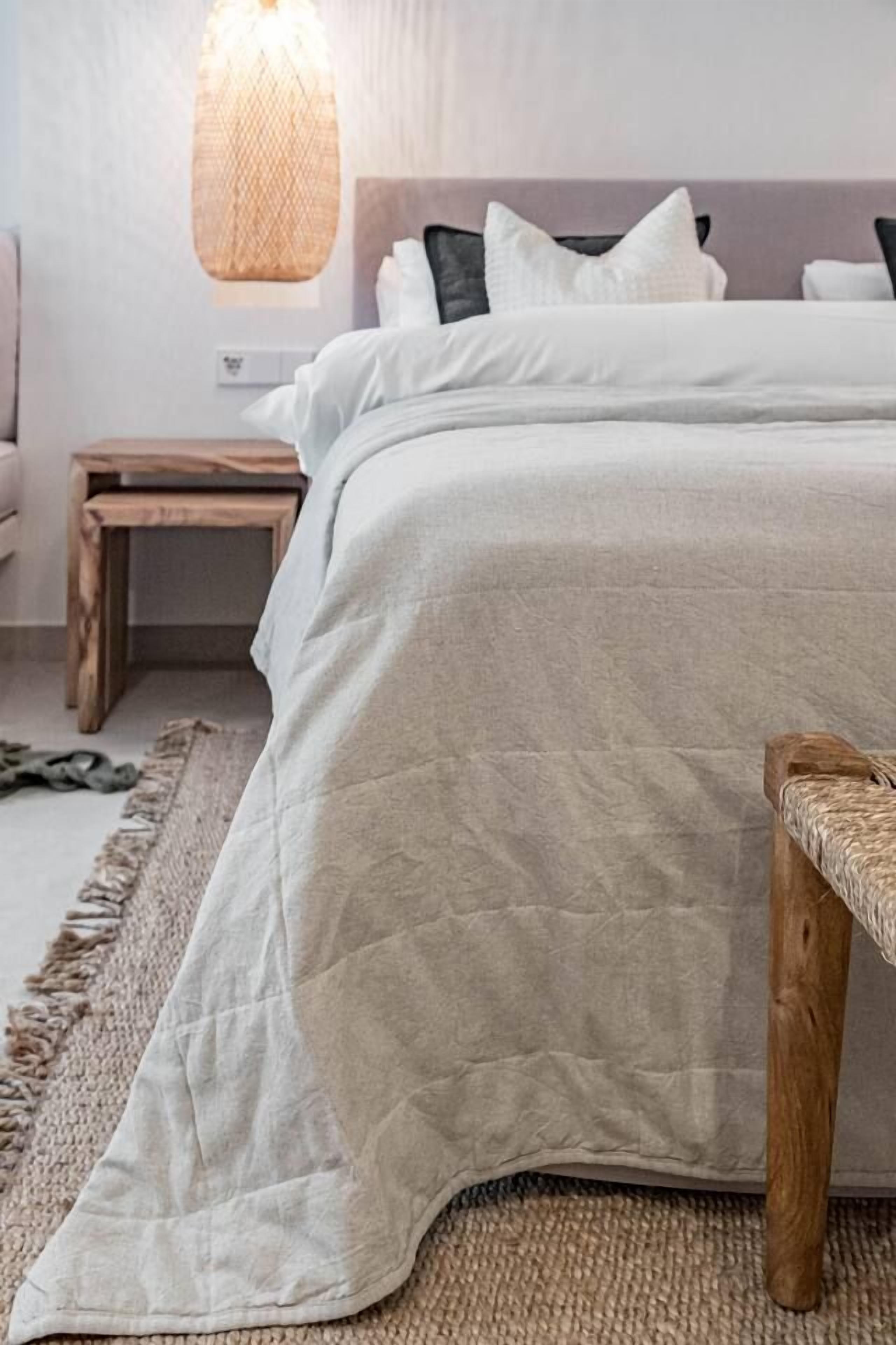 Quarto com cama, mesa de cabeceira e luminária suspensa.