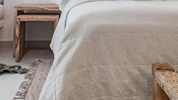Quarto com cama, mesa de cabeceira e luminária suspensa.