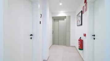 Un pasillo con puertas, un extintor y un cuadro en la pared.