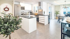 Une cuisine moderne avec des meubles blancs, un îlot central et un coin repas offrant une vue agréable.
