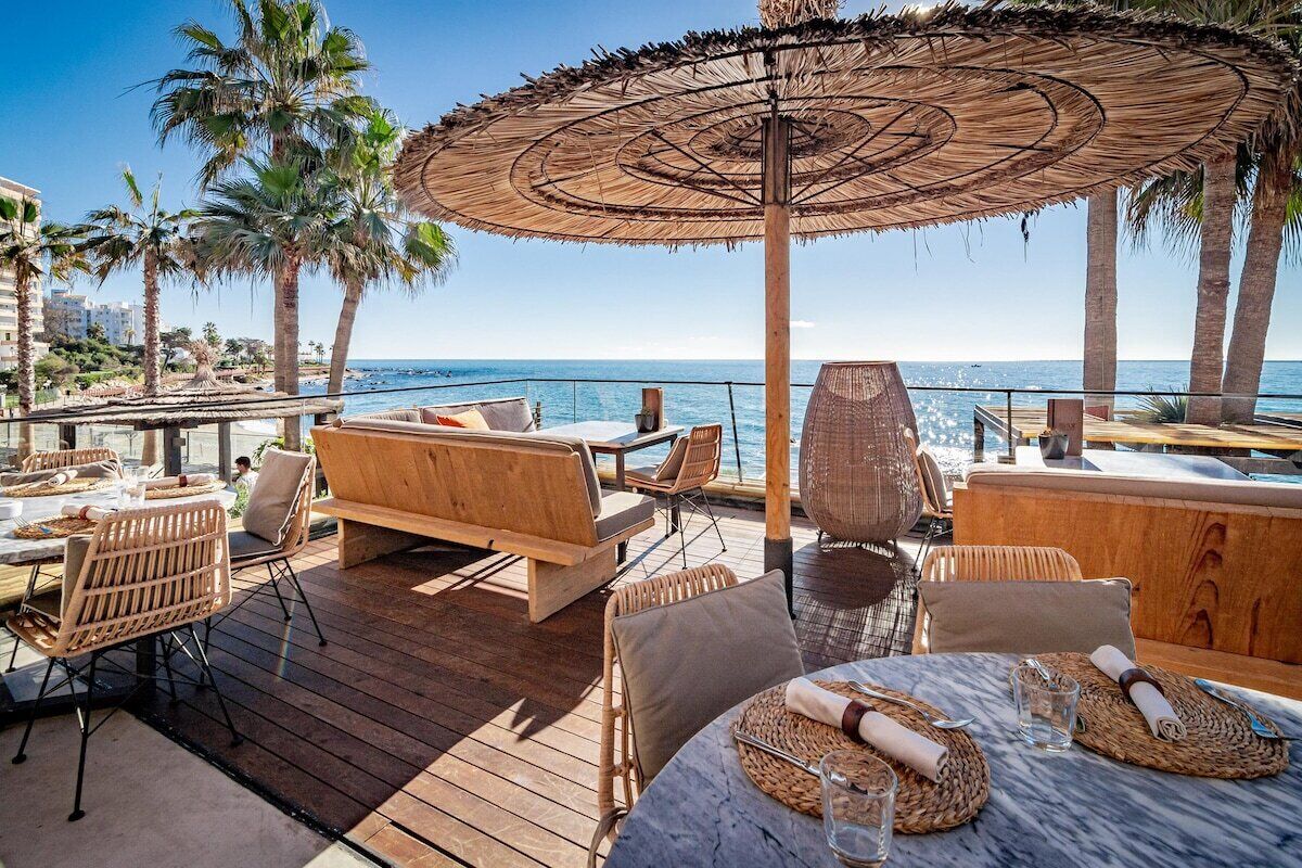 A wooden deck with outdoor seating, including a table and chairs, and a large umbrella providing shade.