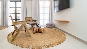 Una sala de estar moderna con un tapete redondo tejido, una mesa de centro de madera, un sofá y un televisor montado en la pared.
