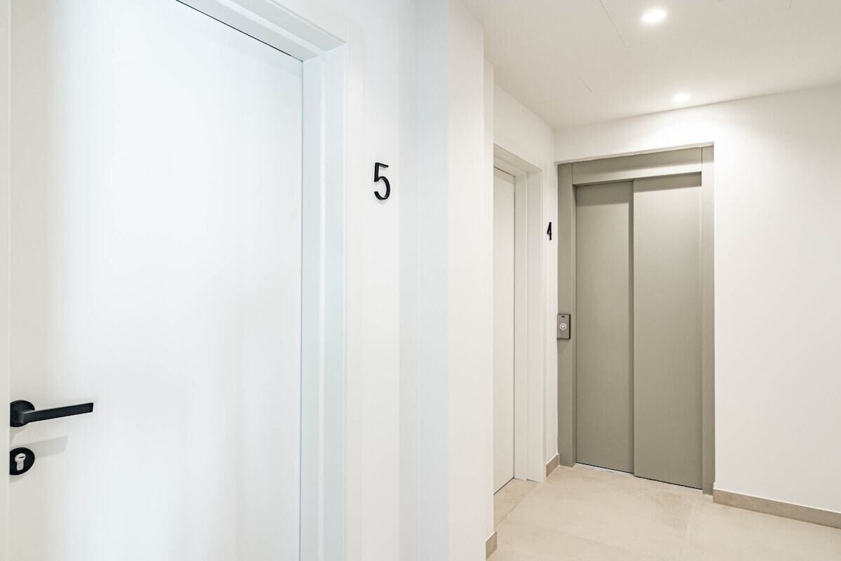 Un couloir avec une porte portant le numéro « 5 » et un ascenseur.