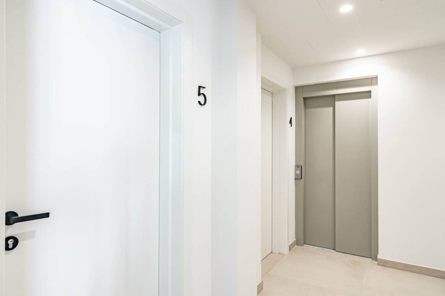 Un pasillo con una puerta numerada 5, un ascensor y una puerta numerada 4.