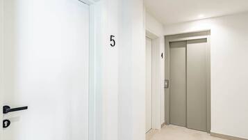 Un pasillo con una puerta numerada 5, un ascensor y una puerta numerada 4.