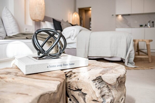 A modern bedroom with a bed, bedside table, and a book titled 'a home away from home' on a wooden stool. - A6- Seaclub Suites by Roomservices (Estepona)