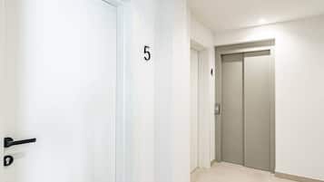 Un pasillo con una puerta numerada 5, un ascensor y una puerta numerada 4.