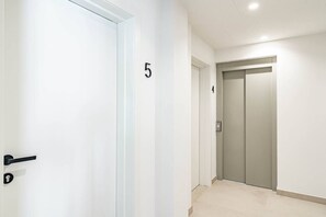 A hallway with a door marked with the number 5, an elevator, and a door marked with the number 4. - A6- Seaclub Suites by Roomservices (Estepona)