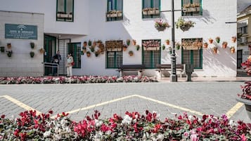 Un bâtiment portant une enseigne indiquant qu’il s’agit d’un établissement d’enseignement permanent, doté d’un espace extérieur aménagé pour s’asseoir et de parterres de fleurs.