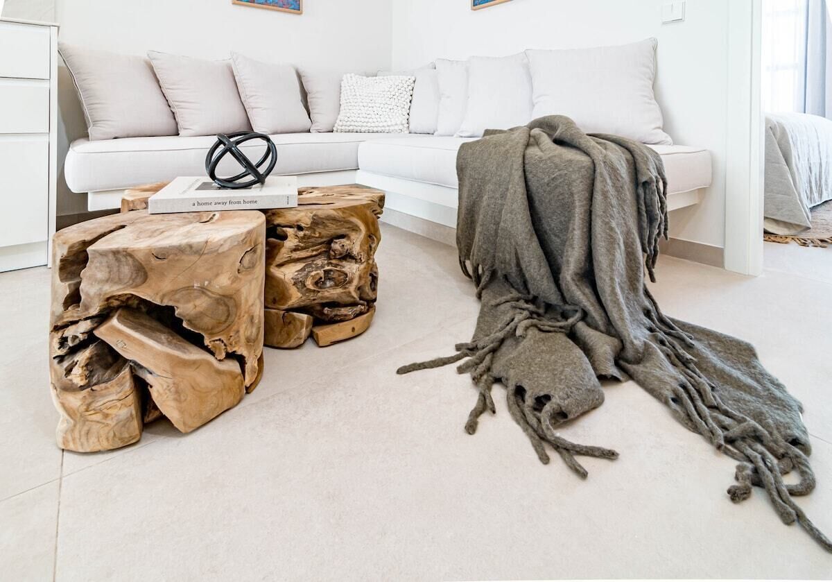 A modern living room with a white sofa, a wooden coffee table, and a blanket draped over the armrest.