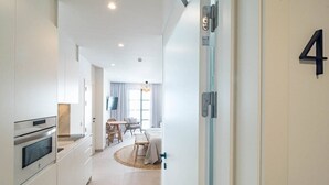 A modern hotel room with a kitchenette, a dining area, and a large bed. - A4- Seaclub Suites by Roomservices (Estepona)