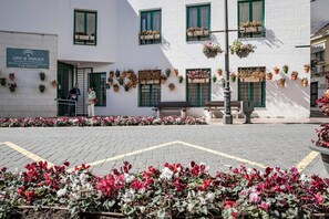 A building with a sign indicating it is a permanent educational institution, outdoor seating, and flower beds. - Seaclub Suites by Roomservices (Estepona)