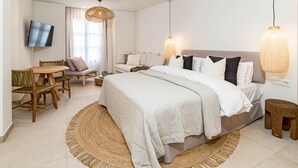 A modern bedroom with a large bed, a round woven rug, a wooden table, and a TV mounted on the wall. - A1- Seaclub Suites by Roomservices (Estepona)
