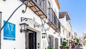 A white building with a sign indicating it is a hotel. There are potted plants outside and a street in front. - A1- Seaclub Suites by Roomservices (Estepona)