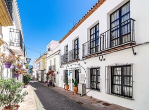 A narrow street lined with white buildings, each with black metal balconies and large windows. - A1- Seaclub Suites by Roomservices (Estepona)