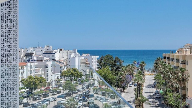 A coastal cityscape with a clear view of the sea, a parking lot, and residential buildings. - Inf46p - Spacious Holiday Home in Estepona (Estepona)