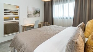A modern hotel room with a large bed, a desk, and a chair. There are two paintings on the wall, a window with curtains, and a hanging light fixture. - Inf46p - Spacious Holiday Home in Estepona (Estepona)