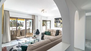 A spacious living room with a large sofa, a glass coffee table, and a view of the outdoor patio. - AB4 - Lovely Holiday Home Walking Distance, Beach (Marbella)
