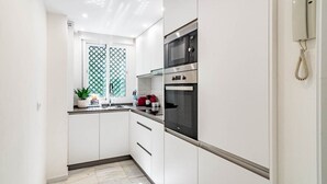 Eine moderne Küche mit weißen Schränken, einer Mikrowelle, einem Backofen und einem Telefon an der Wand.