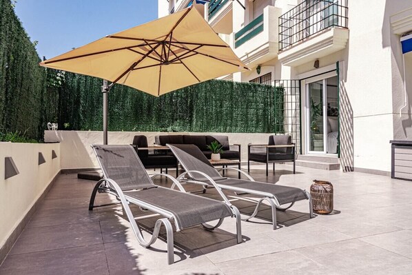 A rooftop terrace with lounge chairs, a large umbrella, and a dining area. - Lcr1- Lovely Ground Floor Apartment, Puerto Banus (Marbella)
