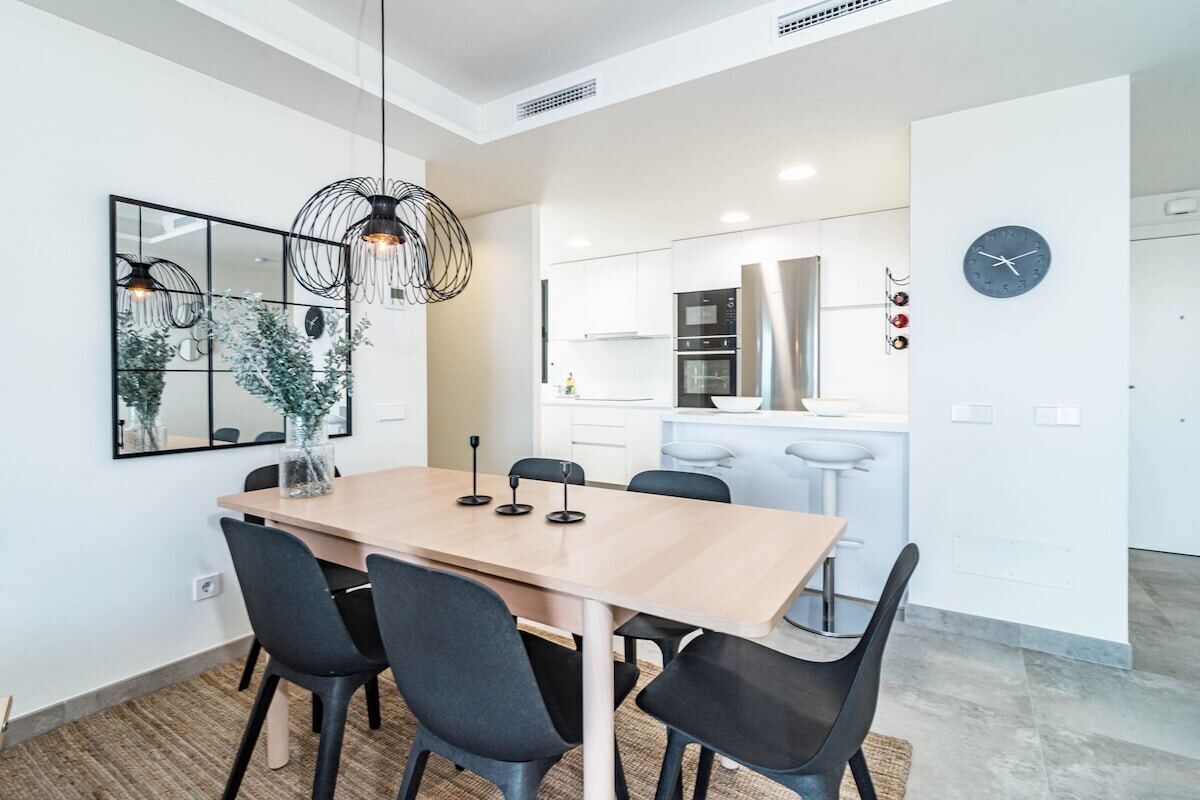 Una cucina moderna con mobili bianchi, un frigorifero in acciaio inossidabile e un forno a microonde.