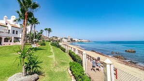 A coastal hotel with a grassy lawn, palm trees, and a beach view. - PL - Beachfront Seaview Aptm - Playa de la Lucera (Mijas)