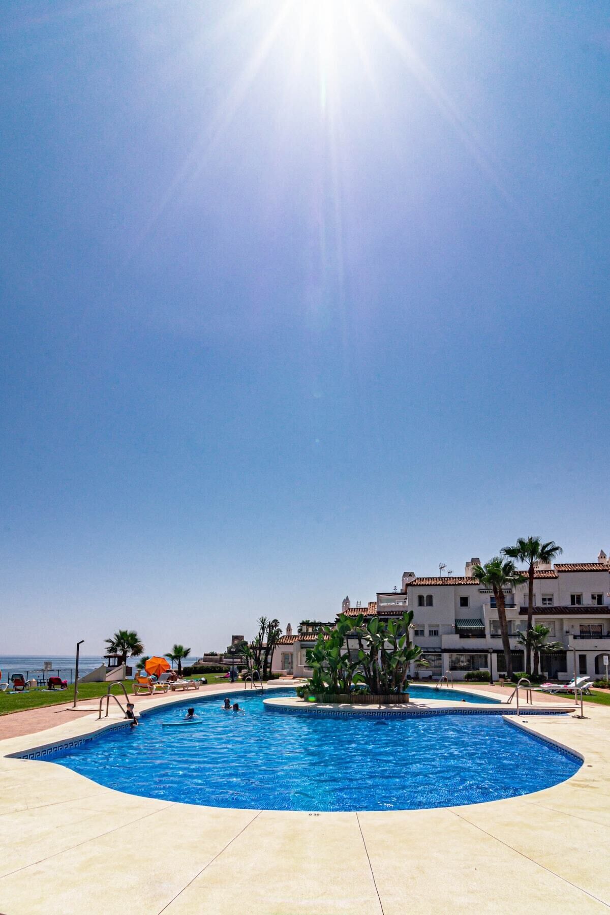 A pool area with a clear sky and a view of the sea.