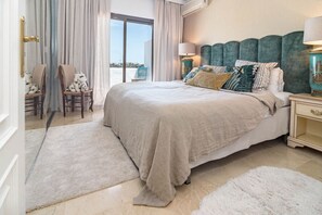 Une chambre avec un grand lit, une table de chevet, une chaise et une vue sur l’extérieur.