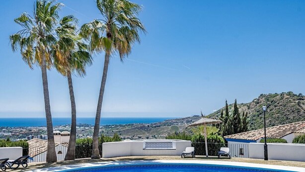 Una piscina con vistas despejadas al mar y colinas al fondo.
