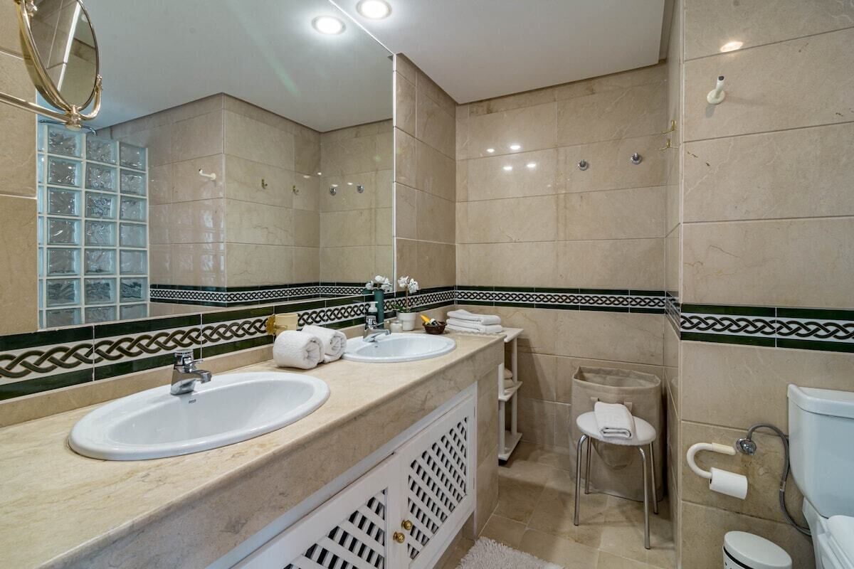Une salle de bain moderne avec deux lavabos, un grand miroir et des toilettes.