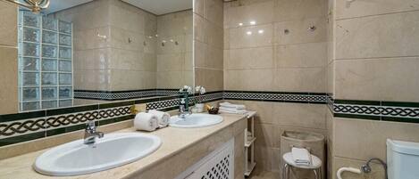 Une salle de bain moderne avec deux lavabos, un grand miroir et des toilettes.