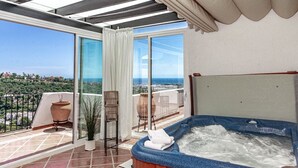 Un balcón con jacuzzi, una planta en maceta y vistas al mar.