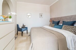 Une chambre à coucher avec un lit, une chaise, une commode et deux tableaux encadrés accrochés au mur.