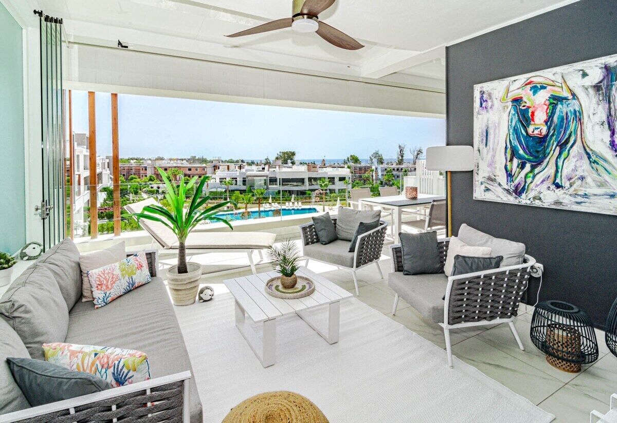 A modern living room with a view of a swimming pool and buildings.