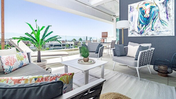 Una zona relax esterna moderna con un divano, sedie e un tavolino.