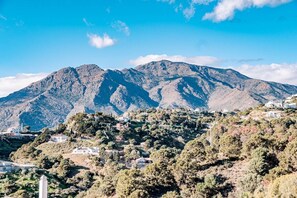 Paisagem montanhosa com edifícios dispersos e uma torre branca imponente.
