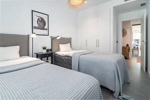 Een moderne slaapkamer met twee bedden, een nachtkastje, een lamp en een lijst met een afbeelding aan de muur.
