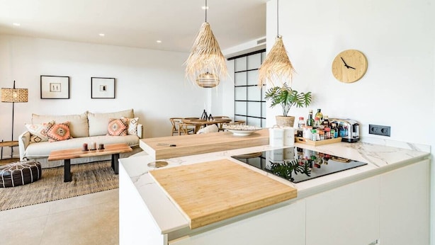 Una cocina moderna con una isla central, muebles de madera y un comedor con mesa y sillas.