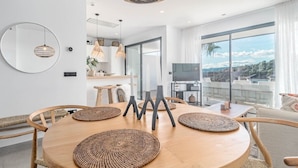 Un comedor moderno con una mesa redonda de madera, individuales tejidos y una lámpara colgante.
