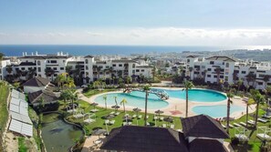Een resort met een centraal gelegen zwembad, meerdere gebouwen en uitzicht op de oceaan.
