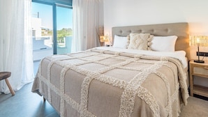 Un dormitorio con una cama grande, una mesita de noche, una lámpara y vistas al exterior.