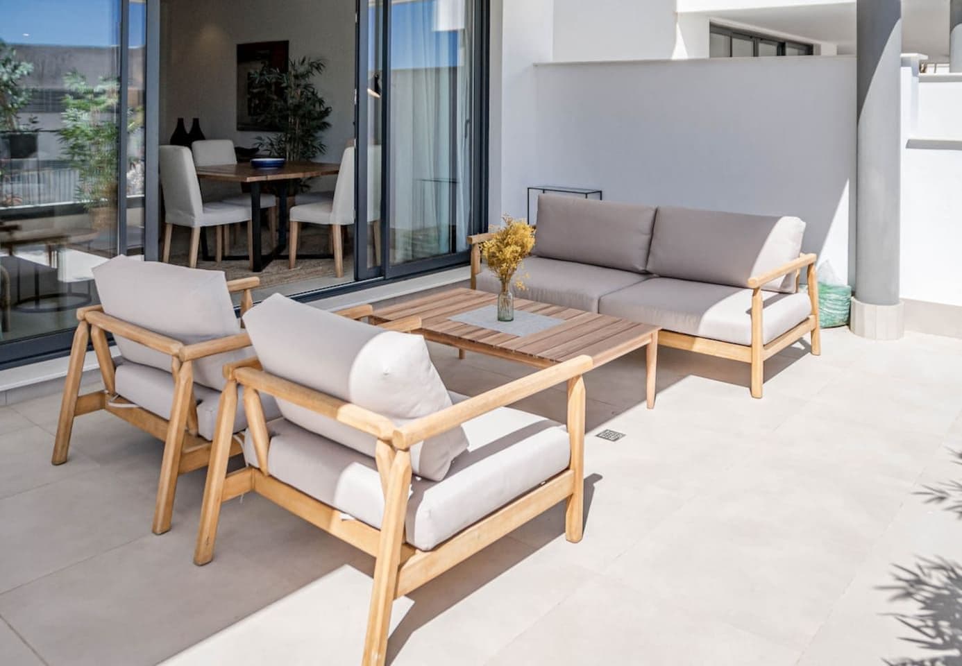 A modern outdoor seating area with a wooden table and two sofas.