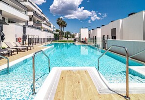 Una piscina con cubierta de madera, barandillas metálicas y sillas de descanso.