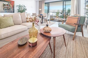 Una sala moderna con un sofá, una mesa de centro redonda y un sillón. Hay un jarrón con flores sobre la mesa.