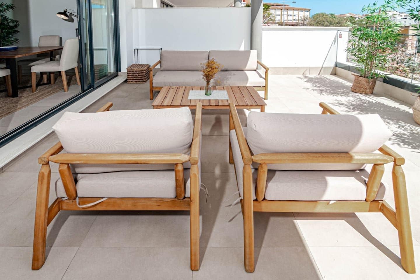 Un espace extérieur moderne aménagé avec des chaises et des tables en bois, une cloison en verre et une vue sur le paysage urbain.