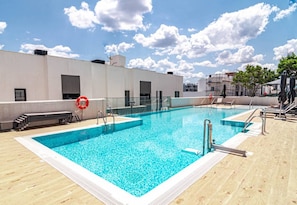 A rooftop swimming pool with clear blue water, surrounded by a wooden deck and a white building. - Lme4bb Sb4bb- Apotel las Mesas by Roomservices (Estepona)