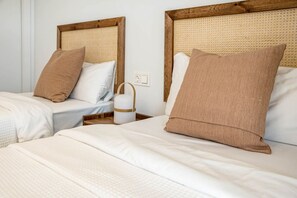 A hotel room with two beds, each with a wooden headboard and a woven headboard. There is a bedside table with a white lamp between the beds. - Lme4bb Sb4bb- Apotel las Mesas by Roomservices (Estepona)